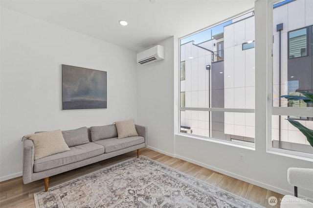 living area with plenty of natural light, wood finished floors, and a wall mounted AC