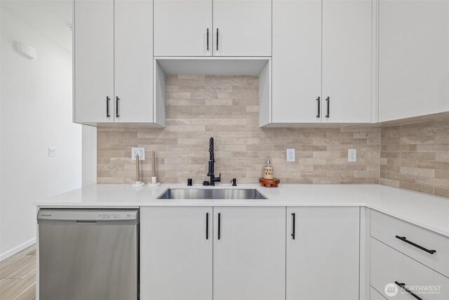 kitchen with dishwasher, white cabinetry, backsplash, and a sink