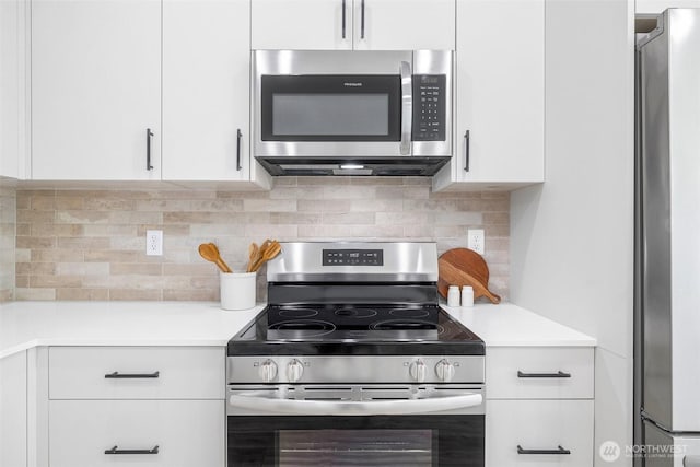 kitchen featuring backsplash, white cabinets, appliances with stainless steel finishes, and light countertops