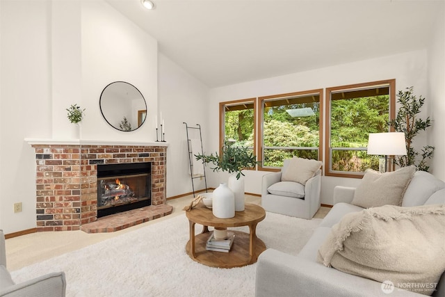 living area with baseboards, lofted ceiling, carpet floors, and a brick fireplace