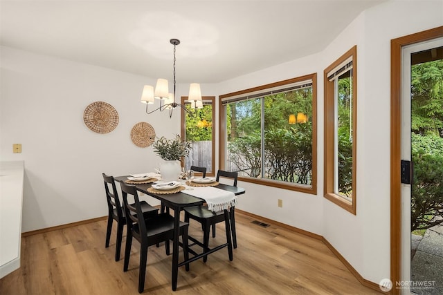 dining room with an inviting chandelier, light wood-style floors, visible vents, and baseboards