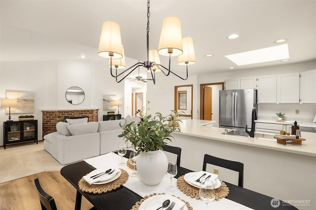 dining space featuring an inviting chandelier, a skylight, recessed lighting, and light wood-type flooring