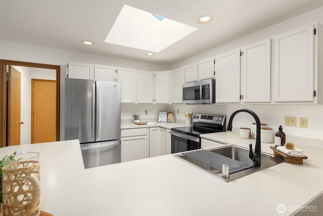 kitchen featuring white cabinetry, recessed lighting, stainless steel appliances, a skylight, and light countertops