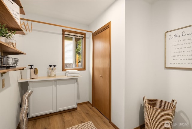 washroom with laundry area, baseboards, and light wood-type flooring