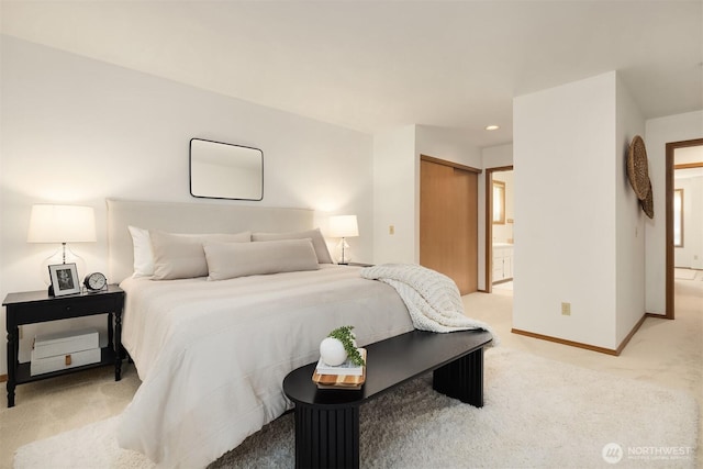 bedroom with baseboards, recessed lighting, a closet, ensuite bathroom, and light colored carpet