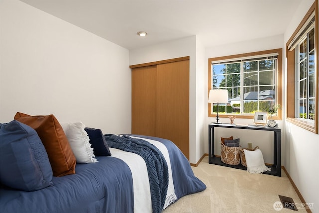 carpeted bedroom featuring a closet and baseboards