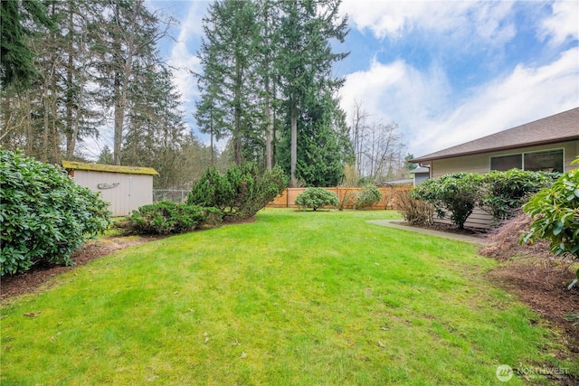 view of yard featuring an outdoor structure, fence, and a shed