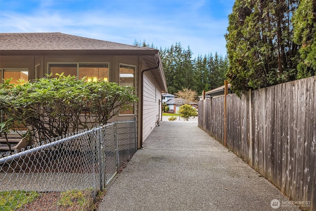 view of property exterior with a shingled roof and fence