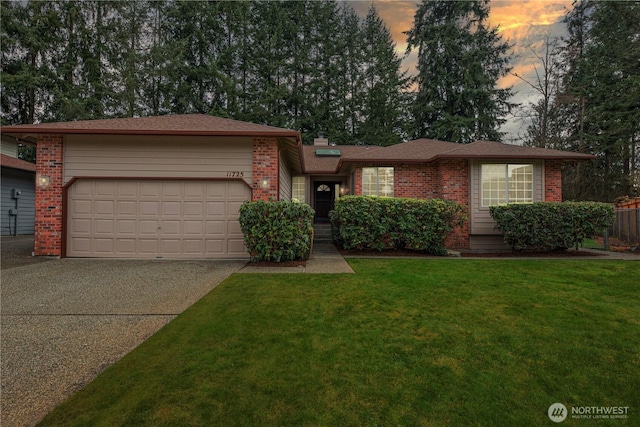 single story home featuring concrete driveway, an attached garage, brick siding, and a front lawn