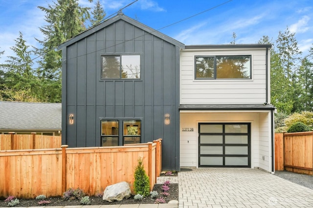 view of front of home featuring decorative driveway, board and batten siding, an attached garage, and fence