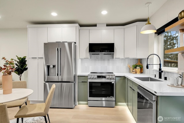 kitchen featuring a sink, decorative light fixtures, appliances with stainless steel finishes, light countertops, and decorative backsplash