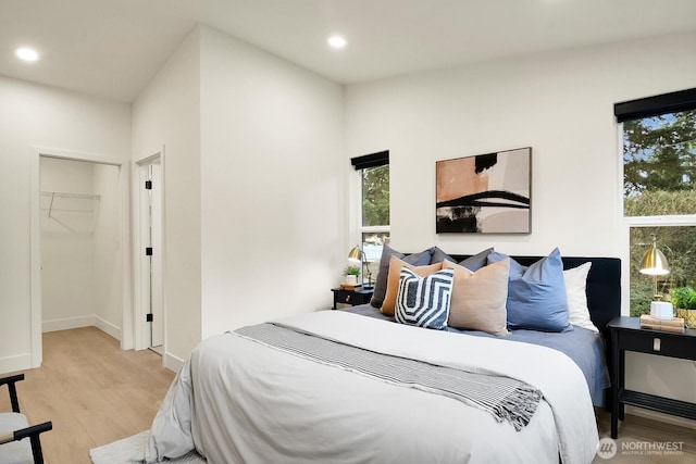 bedroom featuring recessed lighting, baseboards, wood finished floors, and a spacious closet