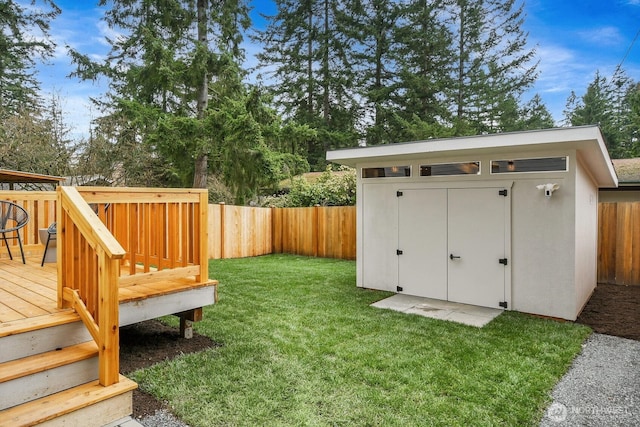 view of yard featuring an outdoor structure, a storage unit, a fenced backyard, and a wooden deck