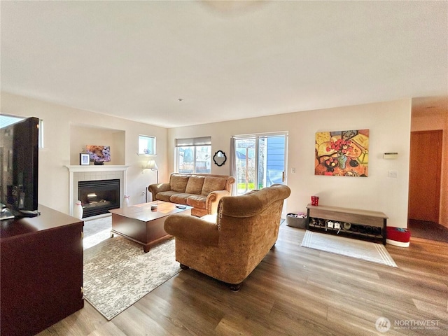 living room with wood finished floors and a tiled fireplace