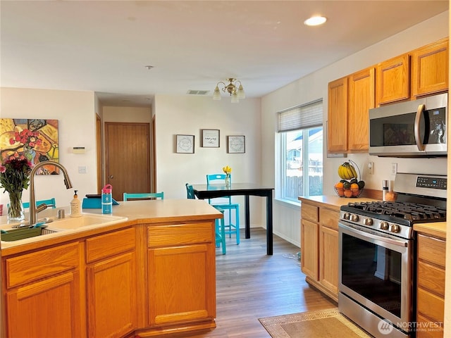 kitchen with visible vents, a sink, light wood-style floors, appliances with stainless steel finishes, and light countertops