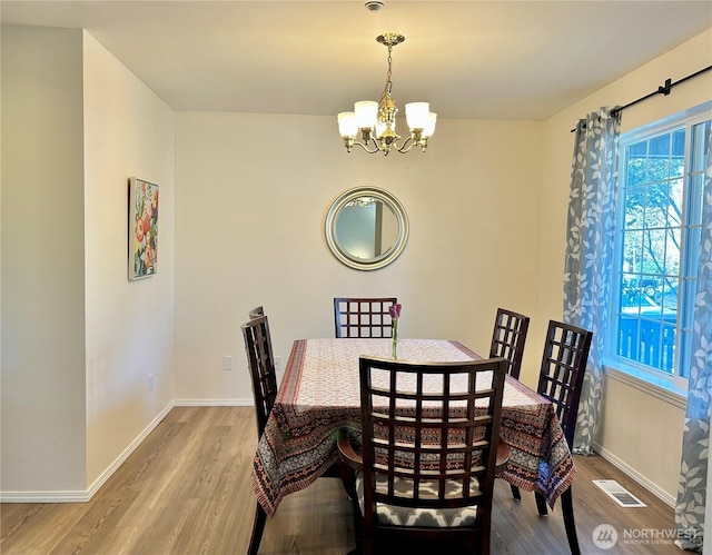 dining space with wood finished floors, baseboards, and a chandelier