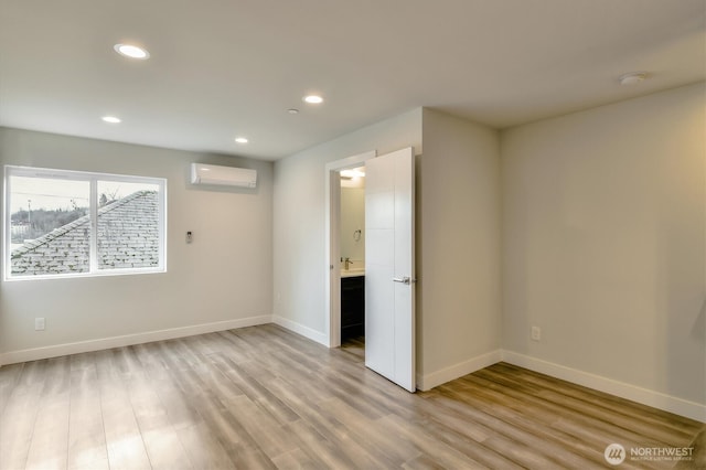 unfurnished room featuring recessed lighting, baseboards, an AC wall unit, and light wood finished floors