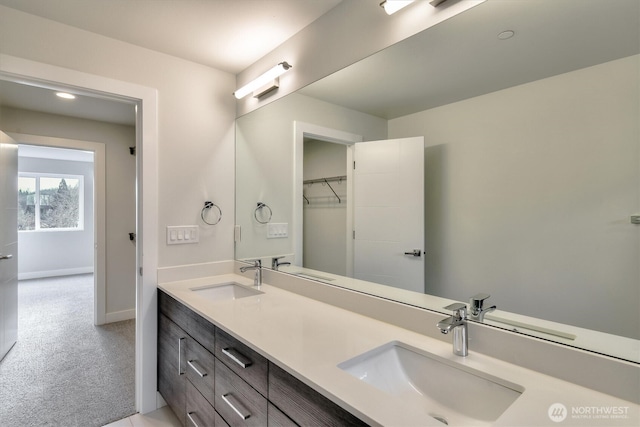 full bathroom featuring double vanity, baseboards, and a sink