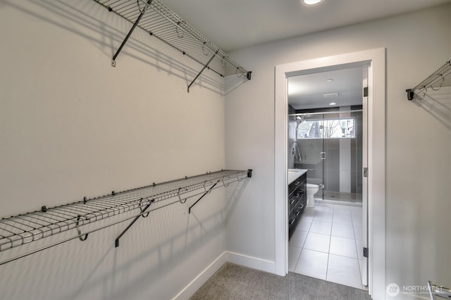 spacious closet featuring light tile patterned floors and light colored carpet