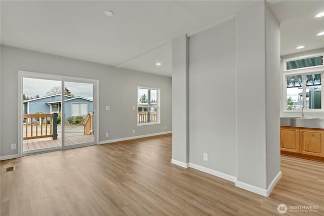 unfurnished living room with baseboards, visible vents, recessed lighting, a sink, and light wood-type flooring