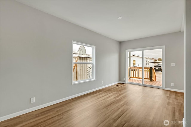 spare room featuring baseboards and wood finished floors