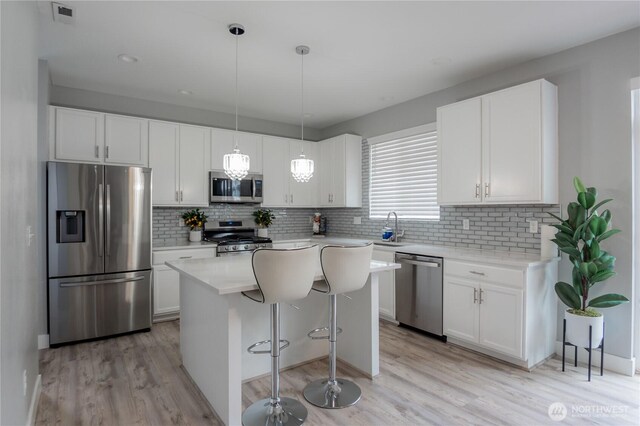 kitchen with visible vents, backsplash, stainless steel appliances, white cabinetry, and a sink