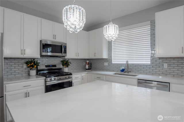 kitchen with a sink, stainless steel appliances, an inviting chandelier, and light countertops