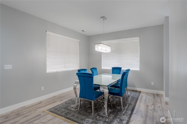 dining area featuring a chandelier, baseboards, and wood finished floors