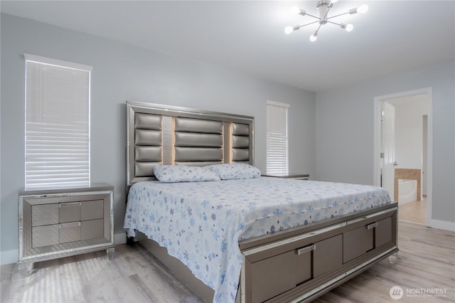 bedroom with a notable chandelier, baseboards, light wood-type flooring, and ensuite bathroom