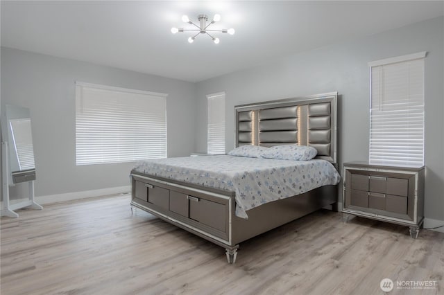 bedroom featuring baseboards, light wood-type flooring, and a chandelier