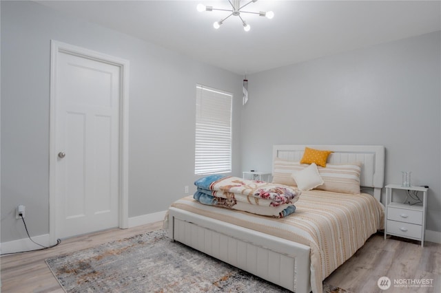 bedroom featuring baseboards, an inviting chandelier, and wood finished floors