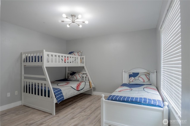 bedroom with multiple windows, wood finished floors, and a chandelier