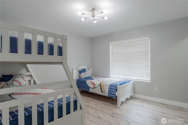 bedroom featuring light wood finished floors, baseboards, and an inviting chandelier