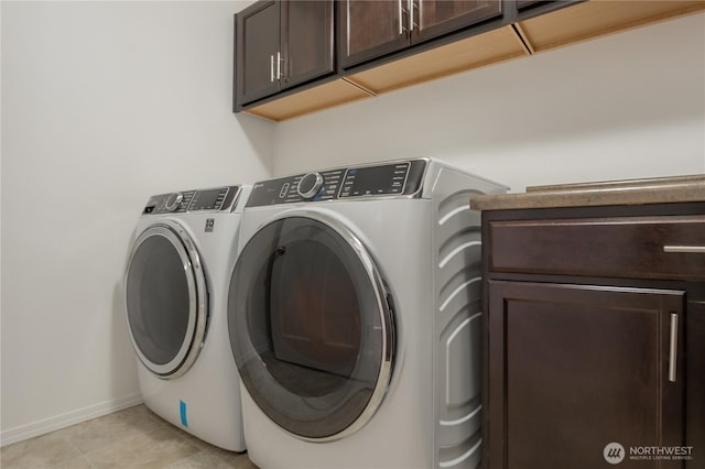 washroom featuring washing machine and dryer, cabinet space, and baseboards