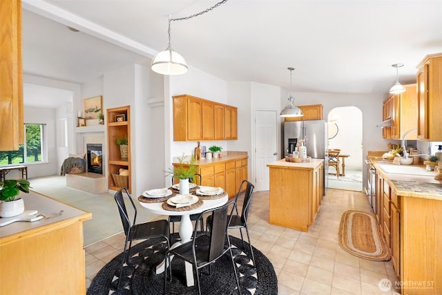 dining room featuring a tiled fireplace, light tile patterned floors, and arched walkways