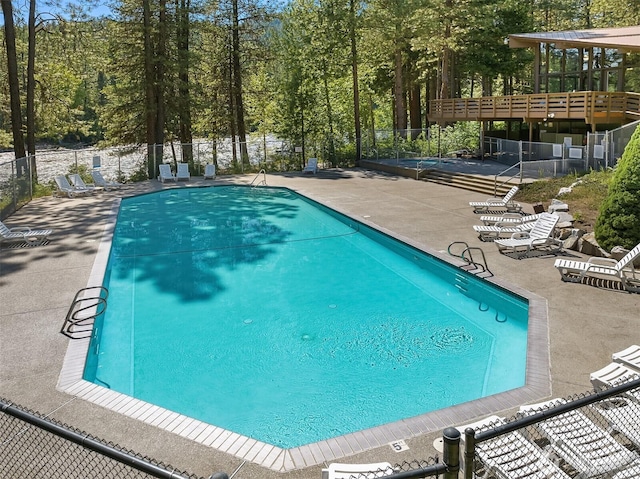 community pool with fence and a patio area