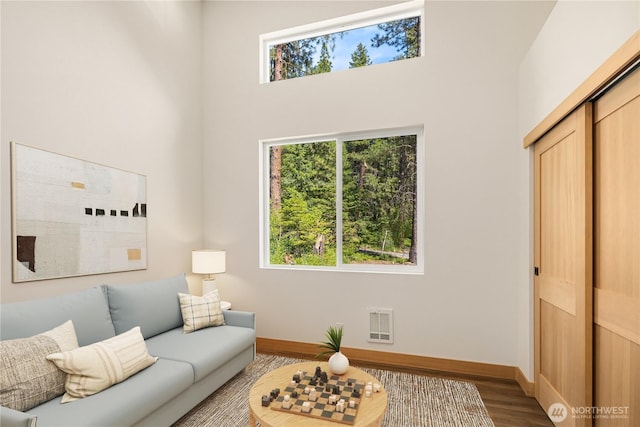 living room featuring baseboards, a high ceiling, and wood finished floors