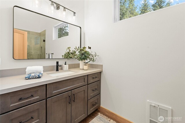 full bath with vanity, a shower stall, wood finished floors, and baseboards