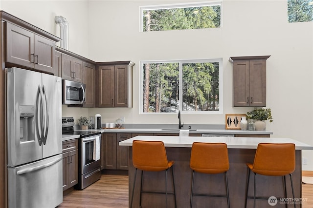 kitchen with a breakfast bar area, light countertops, appliances with stainless steel finishes, light wood-style floors, and a sink