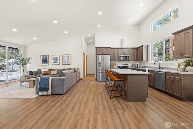 kitchen featuring a breakfast bar area, a kitchen island, high vaulted ceiling, stainless steel appliances, and open floor plan