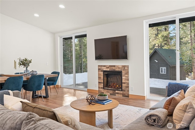 living area featuring recessed lighting, light wood-style floors, and a lit fireplace