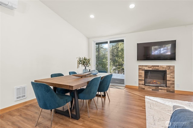 dining room featuring vaulted ceiling, visible vents, baseboards, and wood finished floors