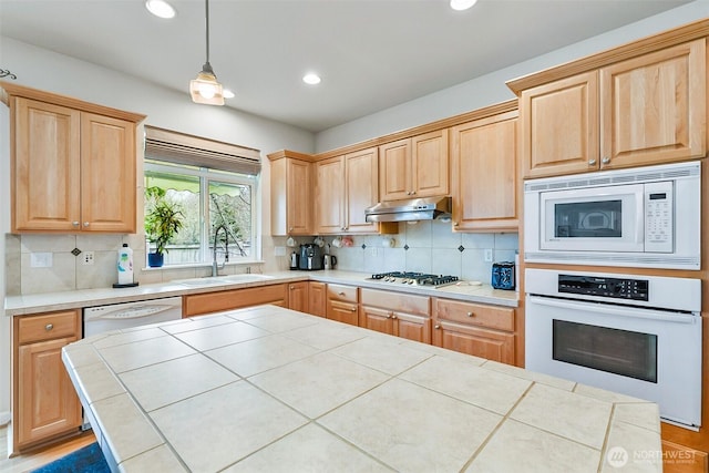 kitchen with light brown cabinets, under cabinet range hood, a sink, backsplash, and white appliances