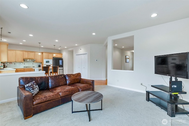 living area with light carpet, recessed lighting, and baseboards