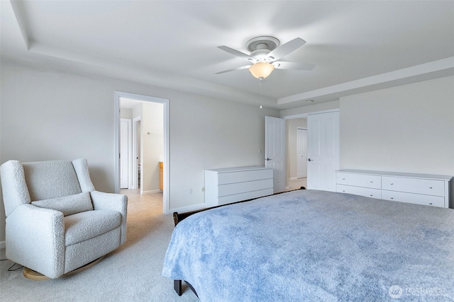 bedroom with baseboards, a raised ceiling, light carpet, and ceiling fan