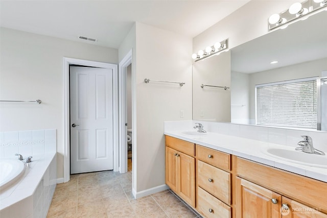 bathroom with double vanity, a garden tub, visible vents, and a sink