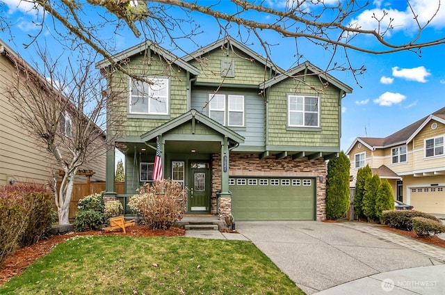 craftsman house featuring stone siding, an attached garage, driveway, and a front lawn