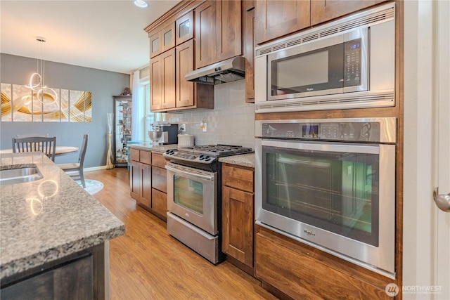 16103 NE 102nd Way, Vancouver, WA 98682 - kitchen with appliances with stainless steel finishes, under cabinet range hood, backsplash, light wood-style floors, and glass insert cabinets