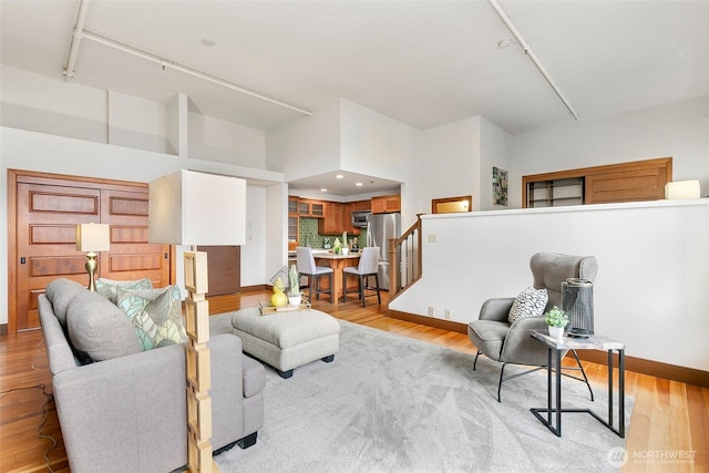 living room featuring recessed lighting, baseboards, light wood-style flooring, and stairs