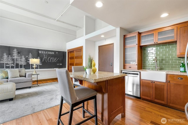 kitchen featuring a sink, light wood-type flooring, dishwasher, and a center island